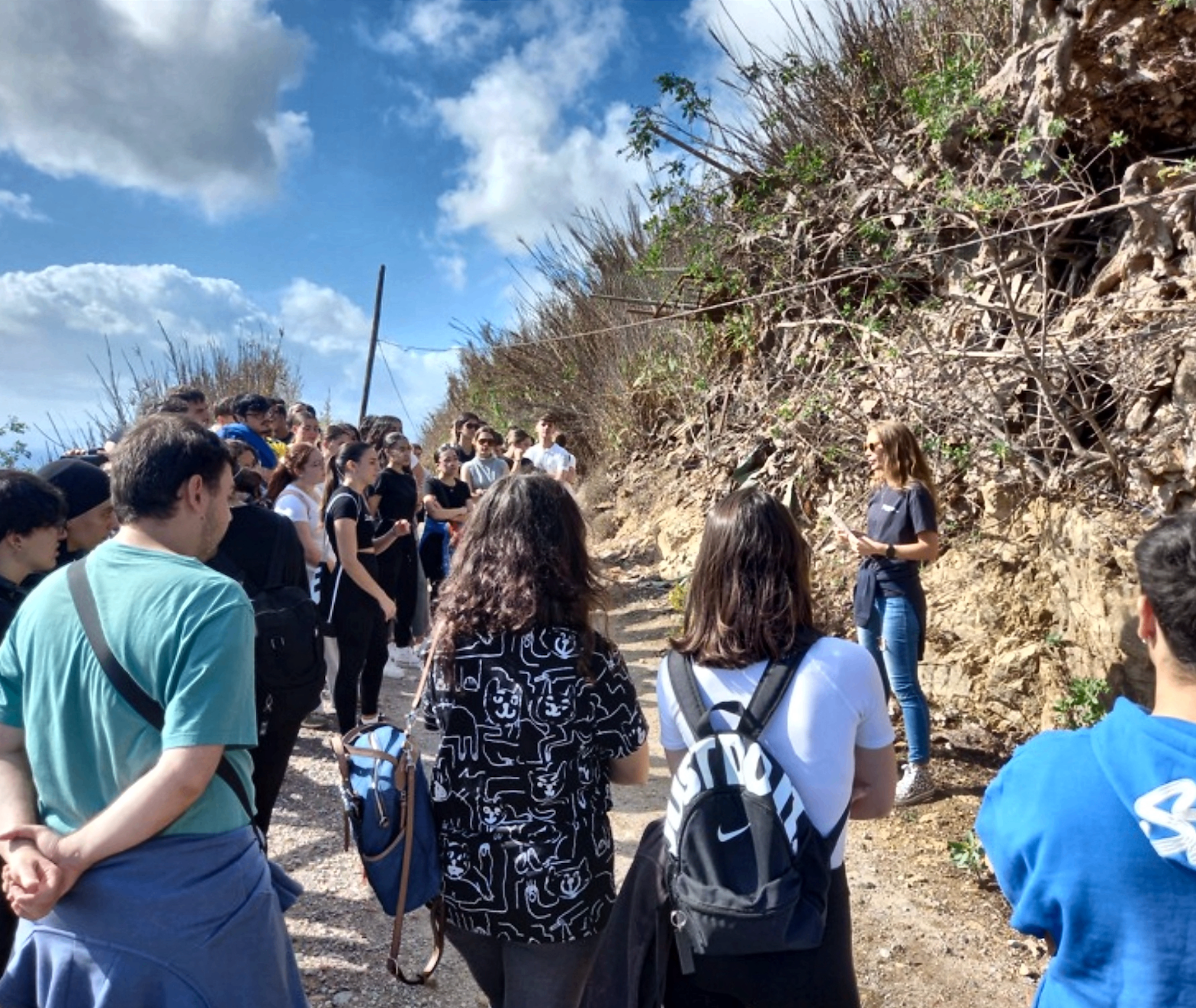 Marichén explicando a un grupo de estudiantes en un camino costero